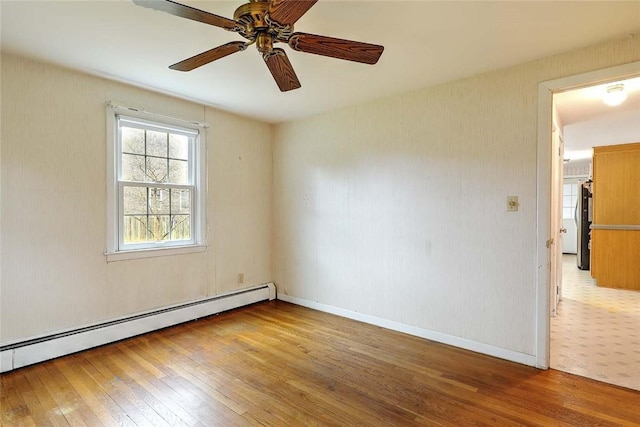empty room with wood-type flooring, baseboard heating, baseboards, and ceiling fan
