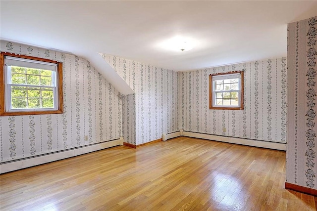 additional living space featuring a wealth of natural light, light wood-type flooring, and a baseboard radiator