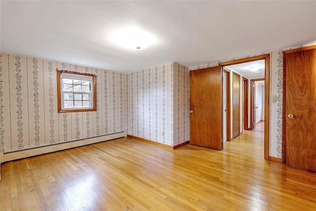 unfurnished room with light wood-type flooring, wallpapered walls, and a baseboard heating unit