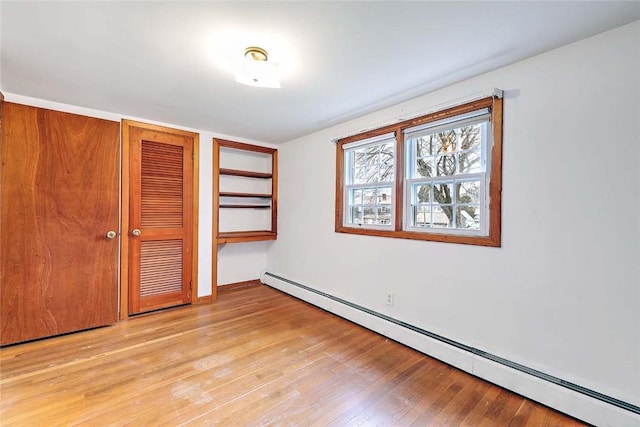 unfurnished room featuring light wood-type flooring, a baseboard heating unit, and baseboards