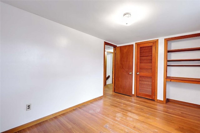 unfurnished bedroom with light wood-style flooring, baseboards, and multiple closets