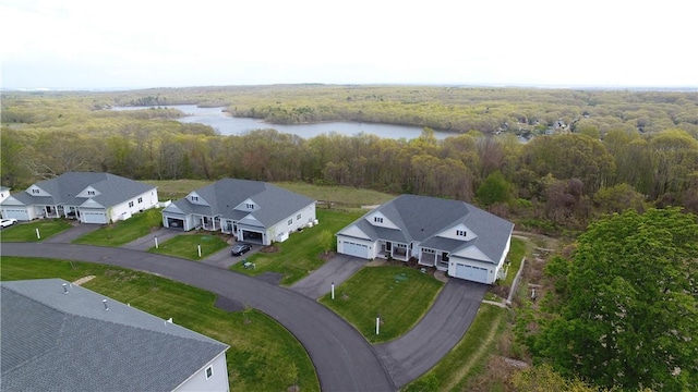 drone / aerial view featuring a water view, a view of trees, and a residential view