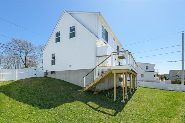 back of house with a gate, a wooden deck, fence private yard, a lawn, and stairs