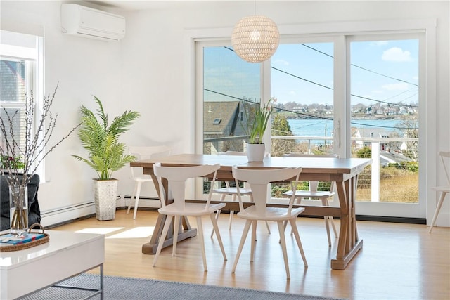 dining space with a wall mounted air conditioner, a healthy amount of sunlight, a water view, and light wood-type flooring