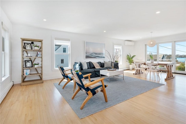 living room featuring an AC wall unit, a wealth of natural light, light wood-style floors, and recessed lighting