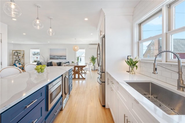 kitchen featuring a wealth of natural light, appliances with stainless steel finishes, blue cabinetry, and a sink