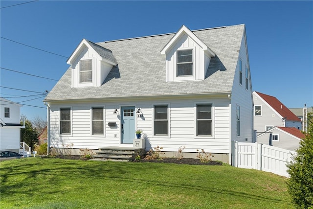 new england style home with fence, roof with shingles, and a front yard