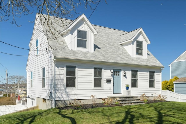 cape cod home featuring fence and a front lawn