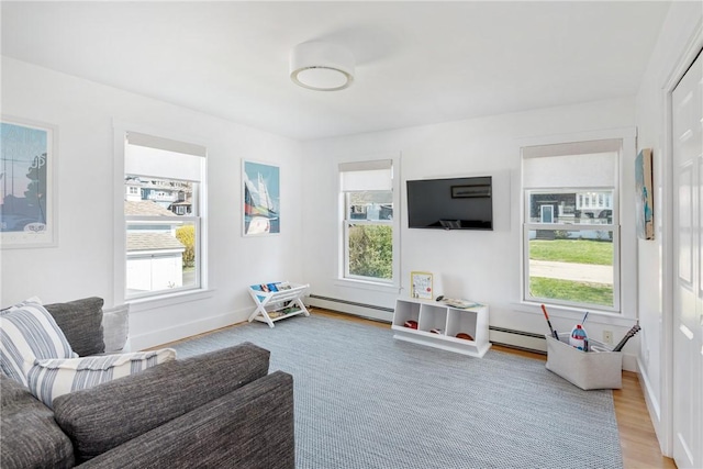 living room with a healthy amount of sunlight, light wood finished floors, and baseboard heating