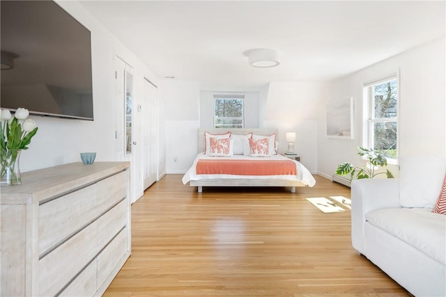 bedroom featuring light wood-style flooring, baseboards, and multiple windows
