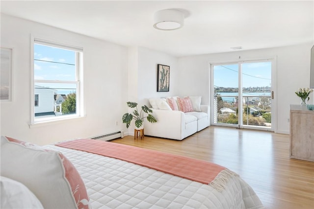 bedroom featuring a baseboard heating unit, light wood-style flooring, and visible vents