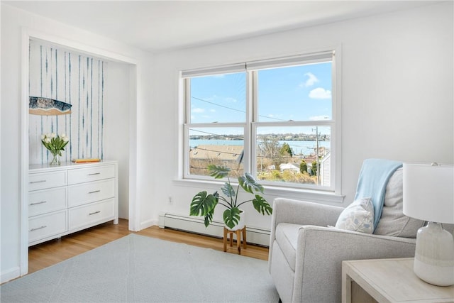 sitting room with baseboards, baseboard heating, wood finished floors, and a water view