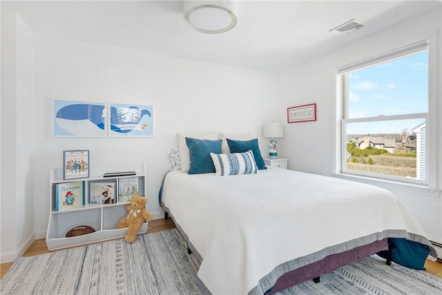 bedroom featuring baseboards, wood finished floors, and visible vents