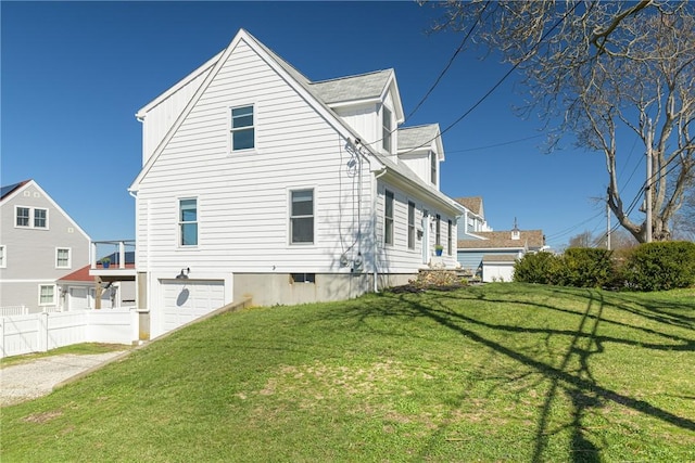 view of side of property featuring a garage, a lawn, and fence