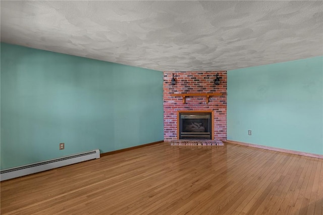 unfurnished living room with baseboards, a brick fireplace, a baseboard radiator, a textured ceiling, and hardwood / wood-style floors