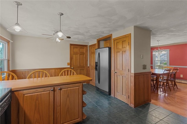 kitchen featuring stainless steel fridge, wooden walls, a ceiling fan, wainscoting, and dishwasher