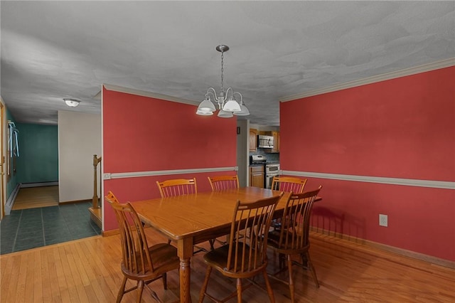 dining room with wood finished floors, a notable chandelier, ornamental molding, and baseboards
