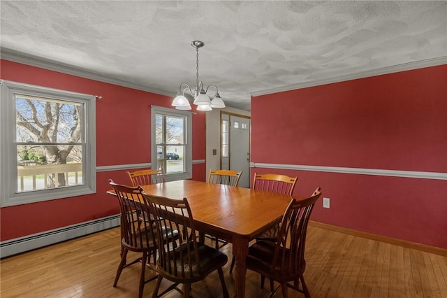 dining space with crown molding, a chandelier, a baseboard heating unit, wood-type flooring, and baseboards