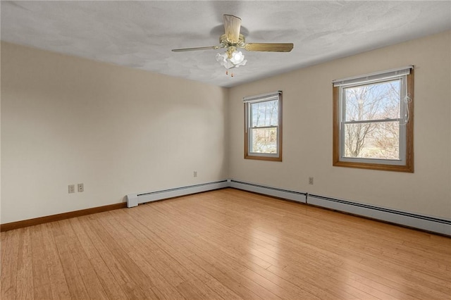 empty room featuring ceiling fan, a baseboard heating unit, wood finished floors, and baseboards