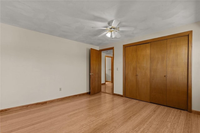 unfurnished bedroom featuring a closet, baseboards, light wood-type flooring, and a ceiling fan