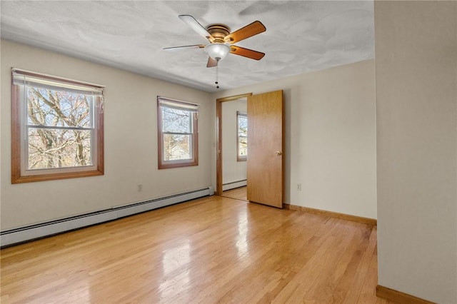 unfurnished room featuring light wood-style floors, a baseboard heating unit, baseboards, and a ceiling fan
