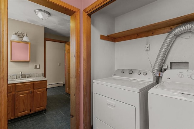 washroom featuring baseboard heating, separate washer and dryer, a sink, and dark tile patterned flooring