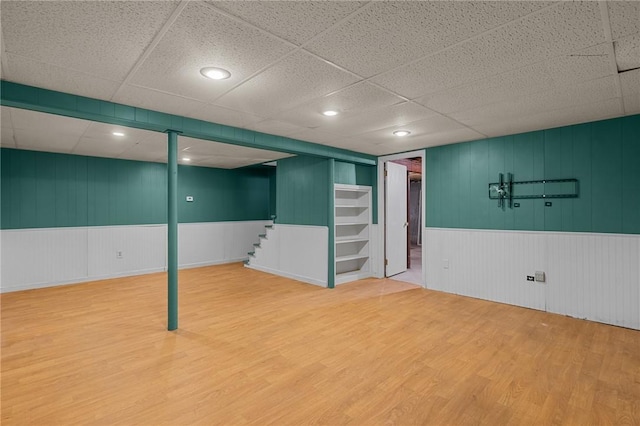 finished basement with wood finished floors, a drop ceiling, and stairway