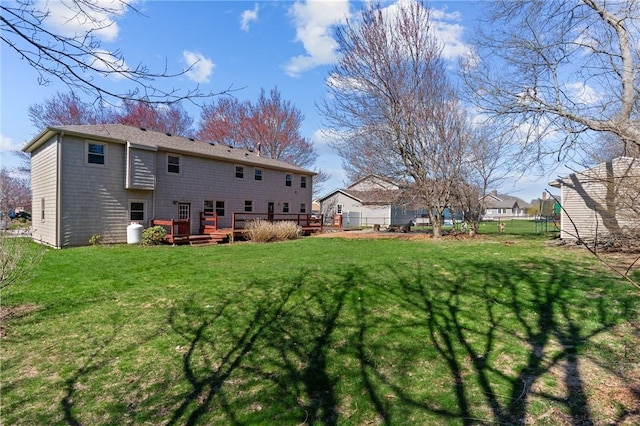 rear view of house featuring a yard, a deck, and fence