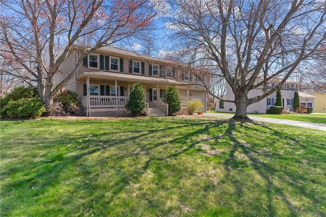 colonial-style house featuring a garage, a front yard, a porch, and driveway