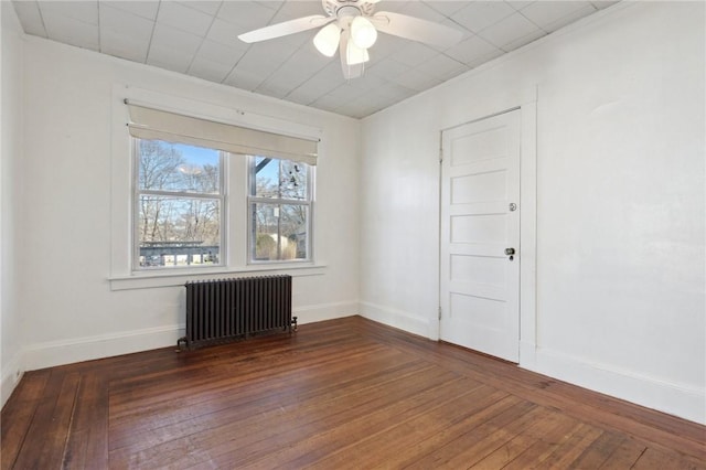 spare room with ceiling fan, baseboards, radiator heating unit, and hardwood / wood-style floors