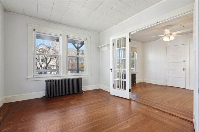 unfurnished room with radiator heating unit, hardwood / wood-style flooring, and baseboards