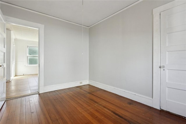 empty room with hardwood / wood-style floors, baseboards, and ornamental molding