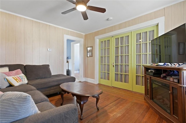 living area featuring hardwood / wood-style floors, ceiling fan, baseboards, and ornamental molding