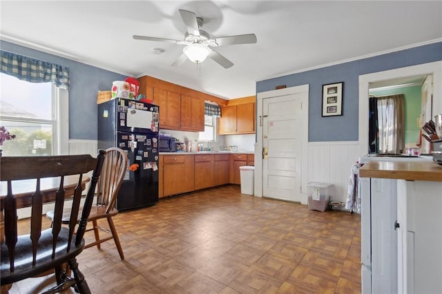 kitchen with wainscoting, black appliances, brown cabinets, and ceiling fan