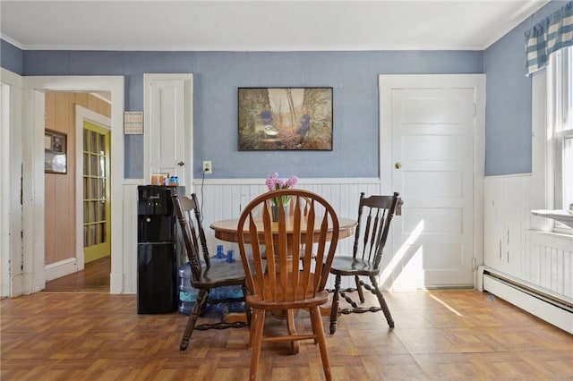 dining space with baseboard heating, ornamental molding, and wainscoting