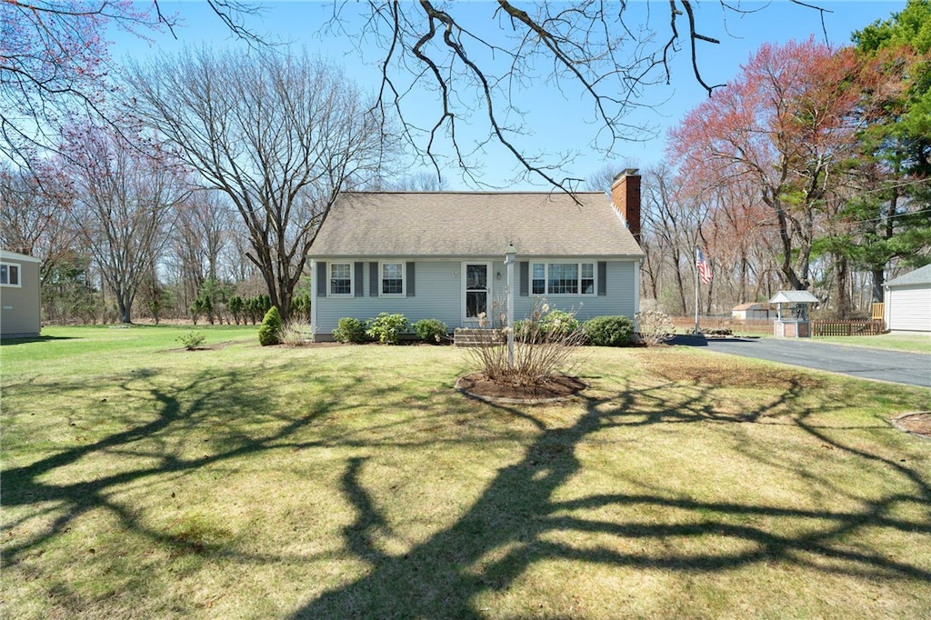 ranch-style house featuring a front yard, aphalt driveway, and a chimney