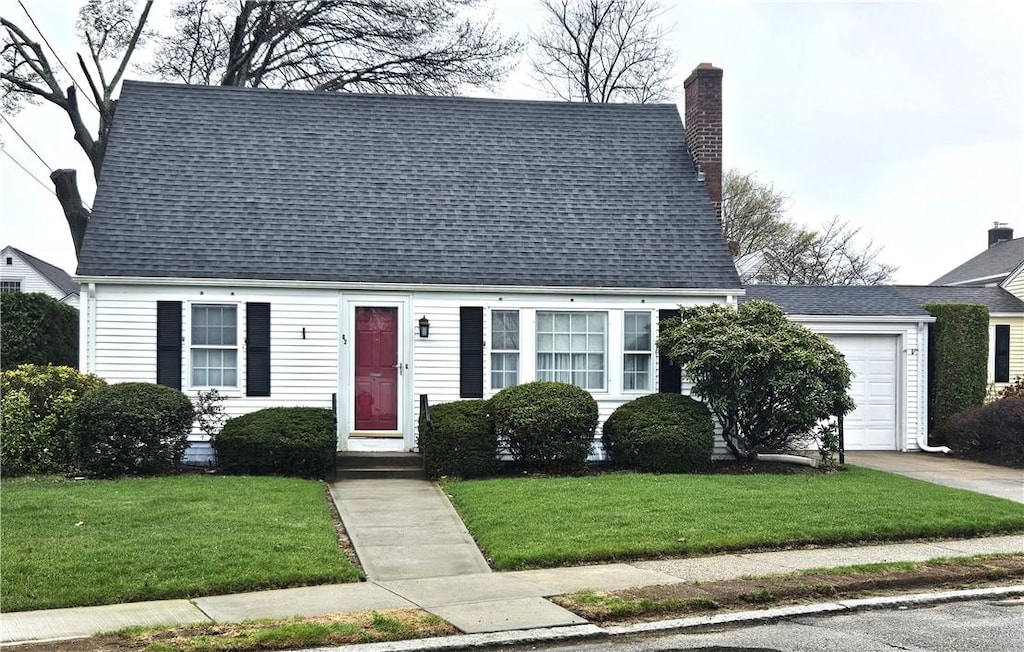 new england style home featuring a garage, a front yard, a chimney, a shingled roof, and concrete driveway