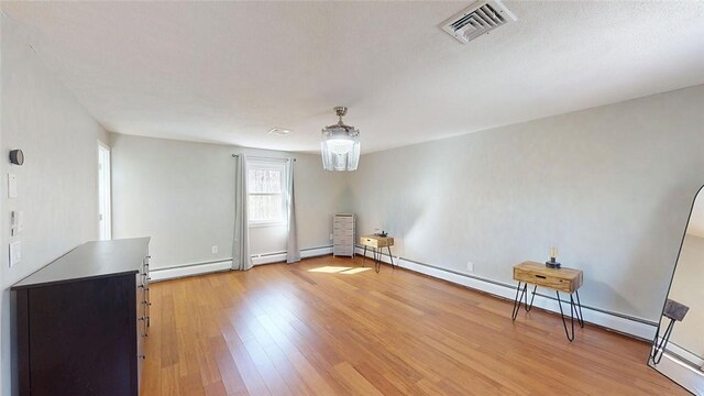 interior space with visible vents, baseboards, a baseboard radiator, baseboard heating, and light wood finished floors