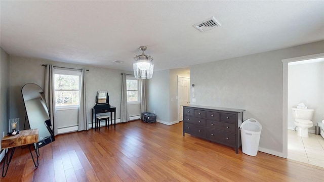 interior space with a chandelier, wood finished floors, baseboards, and visible vents