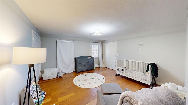 bedroom with baseboard heating and wood finished floors