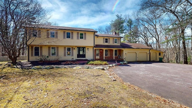 view of front of house featuring a garage, driveway, and a chimney
