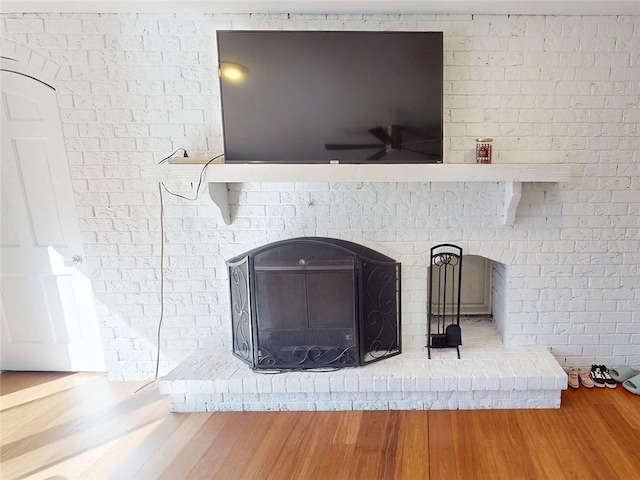 details with ceiling fan, wood finished floors, and a fireplace