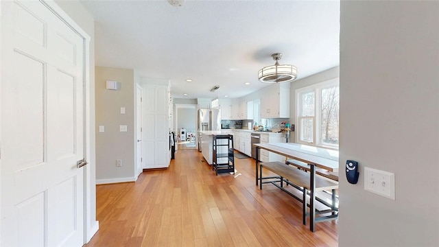 kitchen with light wood-style flooring, white cabinetry, light countertops, and appliances with stainless steel finishes