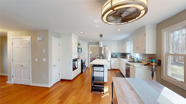 kitchen with light wood-style flooring, light countertops, white cabinetry, and appliances with stainless steel finishes