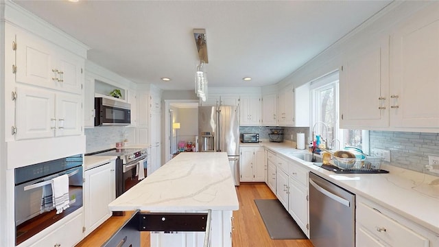 kitchen with white cabinetry, decorative backsplash, appliances with stainless steel finishes, and a sink