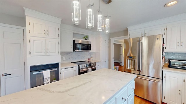 kitchen featuring tasteful backsplash, appliances with stainless steel finishes, white cabinetry, and hanging light fixtures
