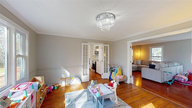 recreation room with crown molding, french doors, a notable chandelier, and wood finished floors