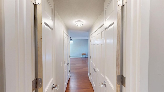 corridor with dark wood-style flooring, a baseboard radiator, and a textured ceiling