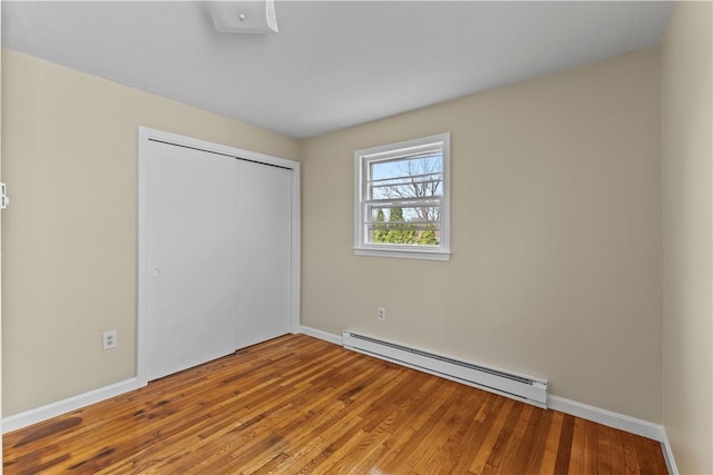 345 Post Rd, Warwick, RI 02888 - unfurnished bedroom featuring baseboard heating, wood finished floors, baseboards, and a closet