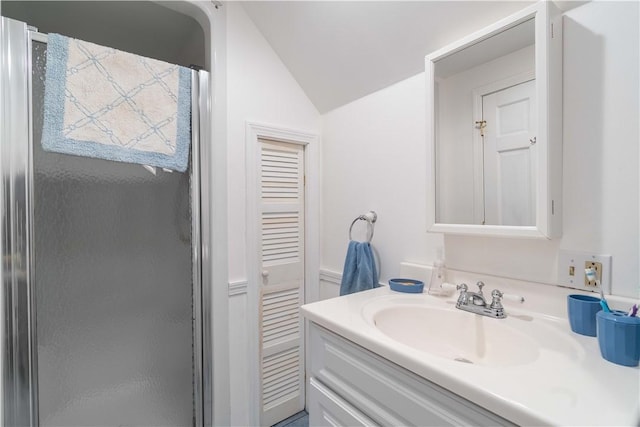 full bathroom featuring a shower stall, vanity, and lofted ceiling